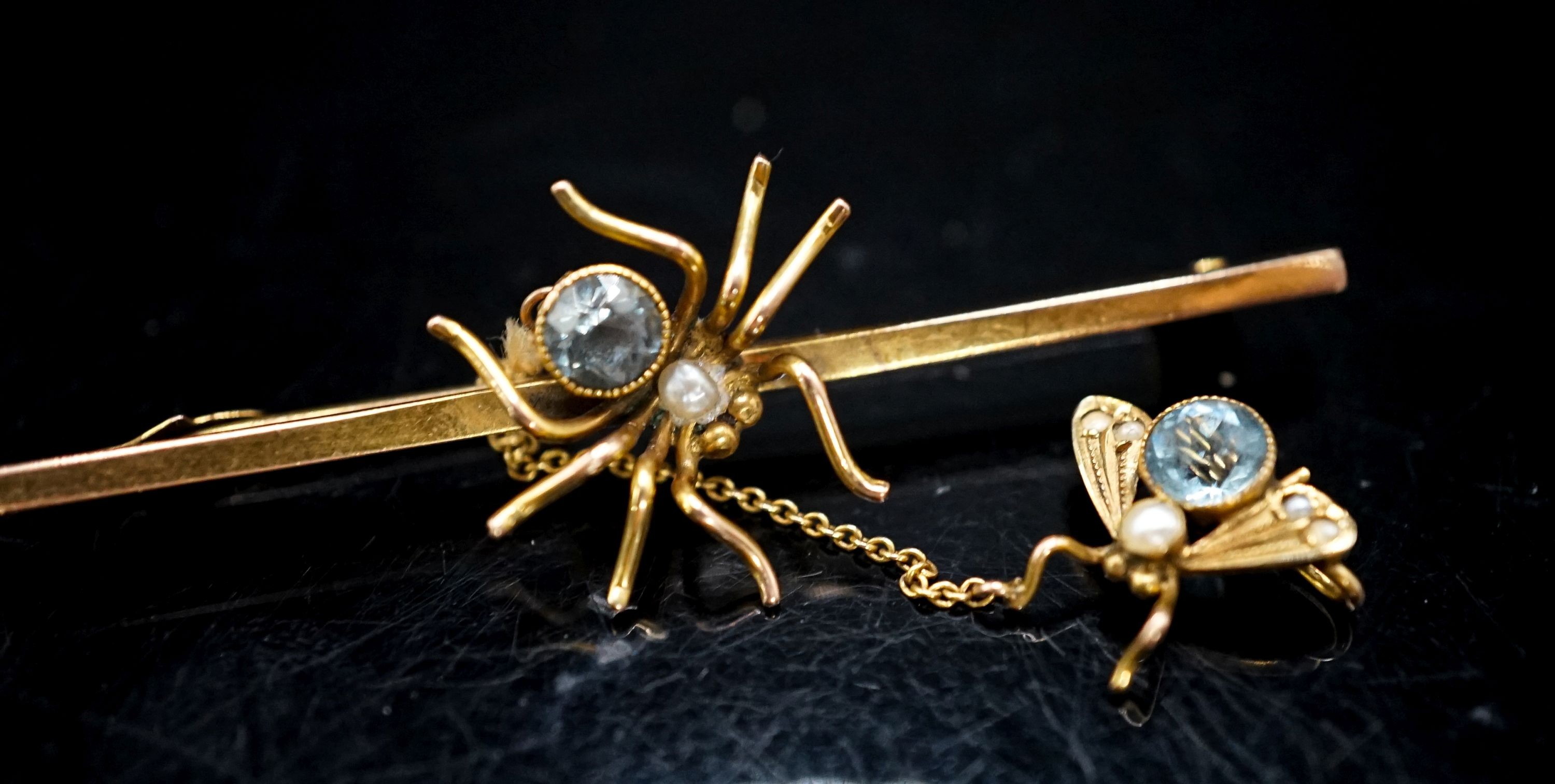 An Edwardian yellow metal and gem set spider bar brooch, 53mm, the safety chain with similar gem set fly, gross 2.8 grams.